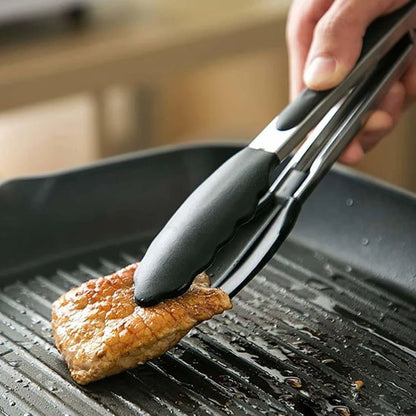 pince qui retourne un morceau de viande dans une poêle