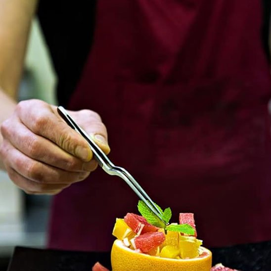 pince qui dépose une feuille de menthe sur un plat