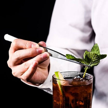 Une pince déposant une branche de menthe dans du thé