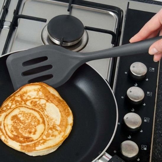 une spatule qui retourne une crêpe dans une poêle