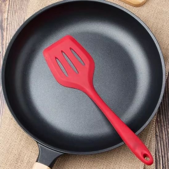 une spatule rouge dans une poêle