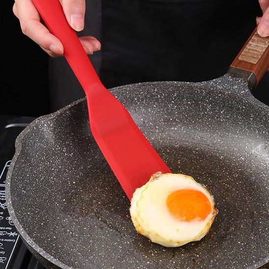 Une spatule avec un œuf dessus une poêle