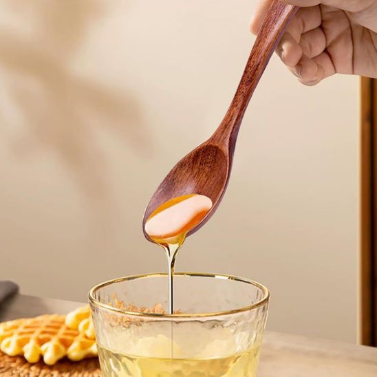 Cuillère à miel versant du miel dans un verre