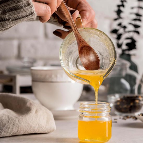 Cuillère à miel versant du miel dans un pot