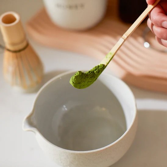 Cuillère à thé versant du thé matcha dans une tasse