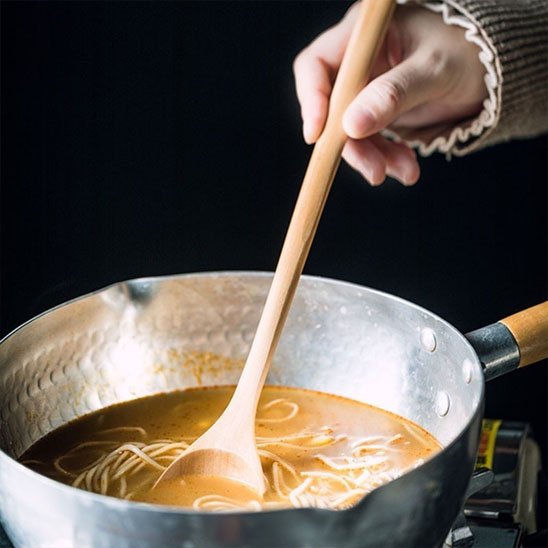 une cuillère qui mélange la soupe dans une casserole