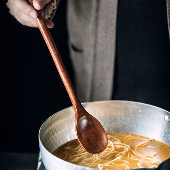 cuillère marron qui tourne la soupe dans un casserole